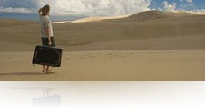 Frau mit Reisekoffer in der Wüste